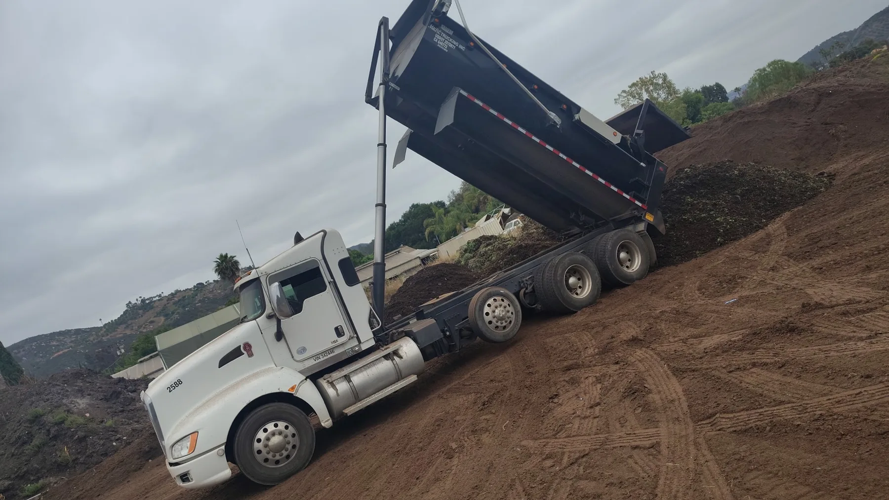 Super 10 dump truck unloading material on a dirt jobsite