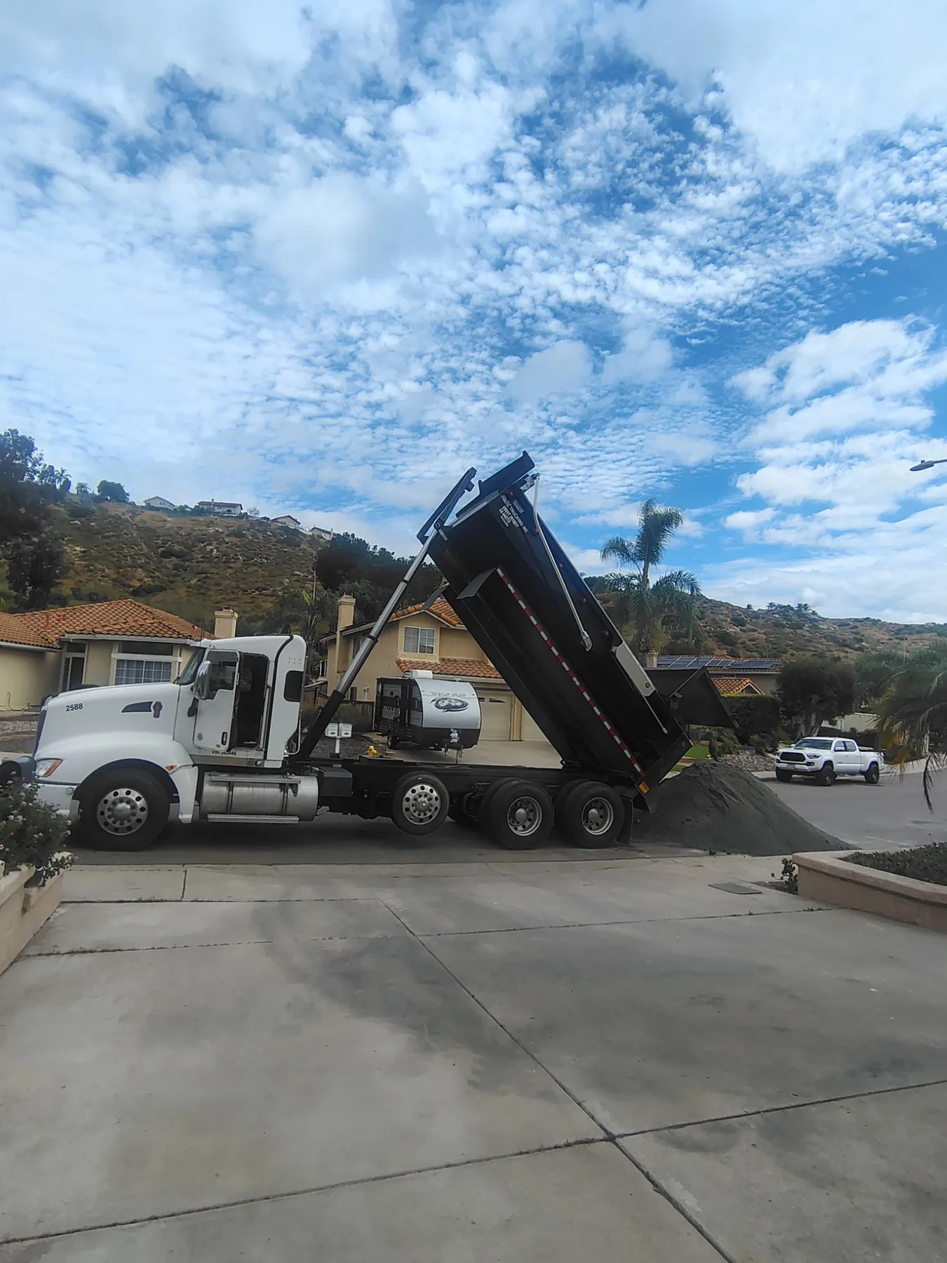 Super 10 dump truck unloading material in a residential driveway